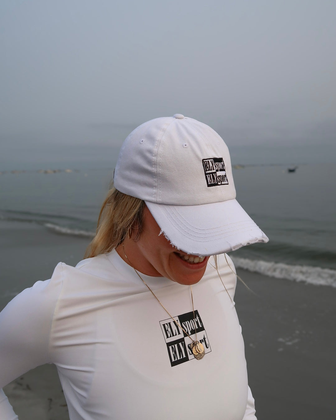 sport white distressed denim hat on model Kat Simmons running beach